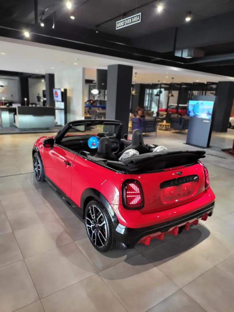 Mini Cooper bekas tipe convertible tampak dari sisi belakang dalam ruangan penyerahan kendaraan showroom.