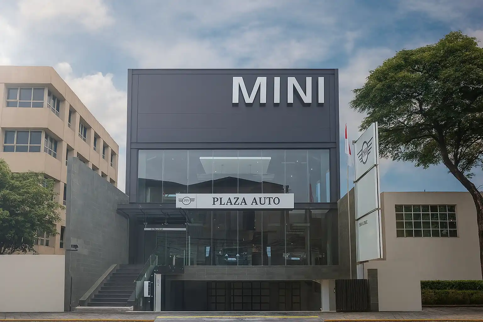 Tampilan depan Dealer Resmi MINI Cooper Plaza Auto dengan desain modern, gedung kaca dua lantai, dikelilingi gedung lain dan pepohonan, menciptakan suasana elegan dan profesional.